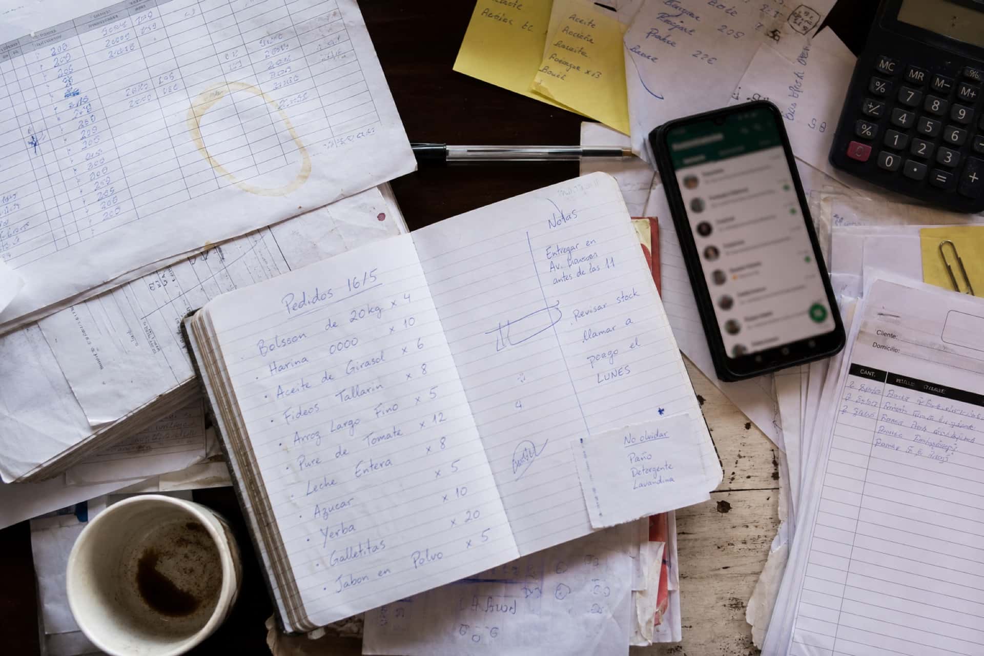 Pedidos, notas y WhatsApp en un escritorio — el trabajo todavía a mano